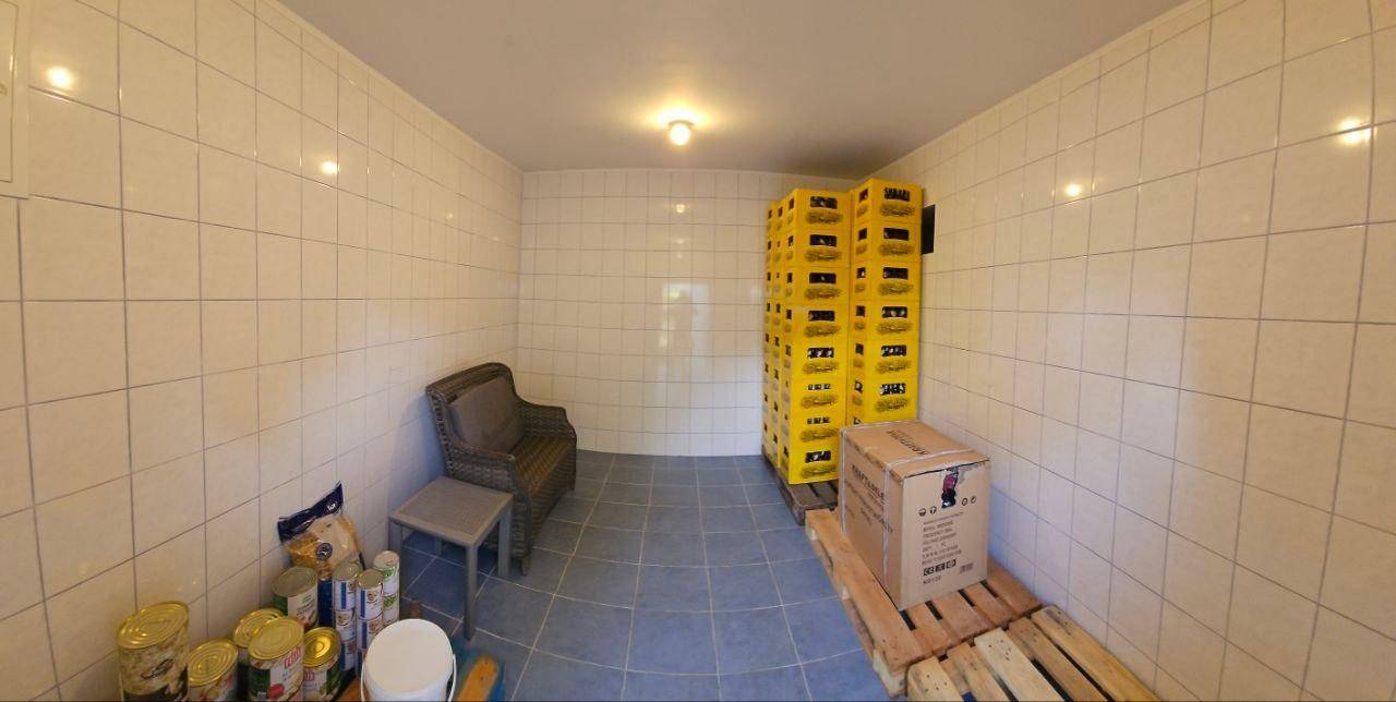 Einfacher Lagerraum mit gestapelten gelben Kisten, einer Sitzgelegenheit und Fliesenboden.