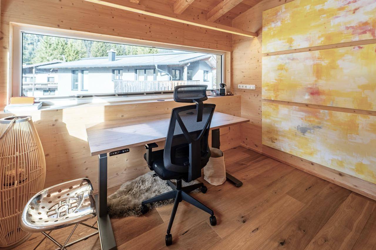 Helles Büro mit großem Fenster, Holzwänden und modernem Schreibtisch.