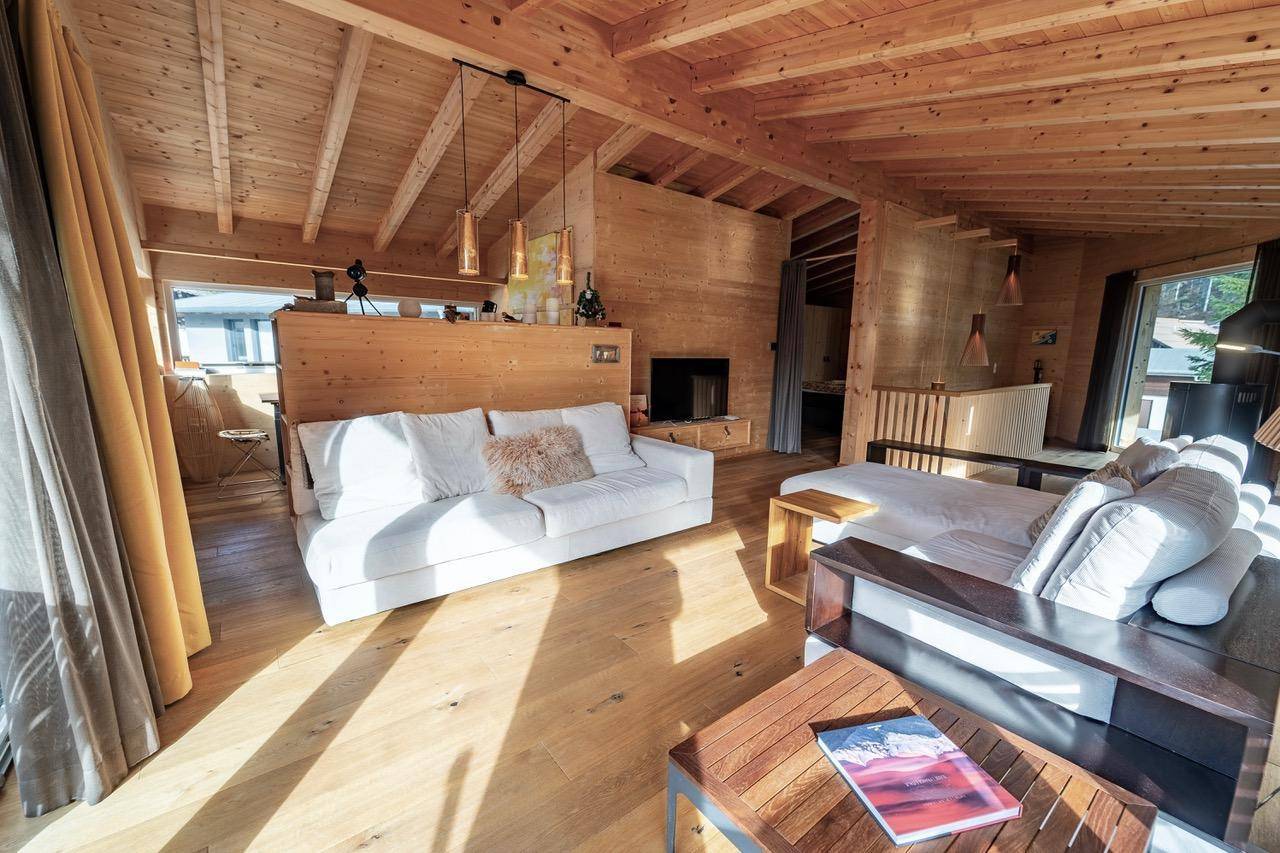 Offener Wohnbereich mit Holzbalkendecke, bequemen Sofas und viel Tageslicht.