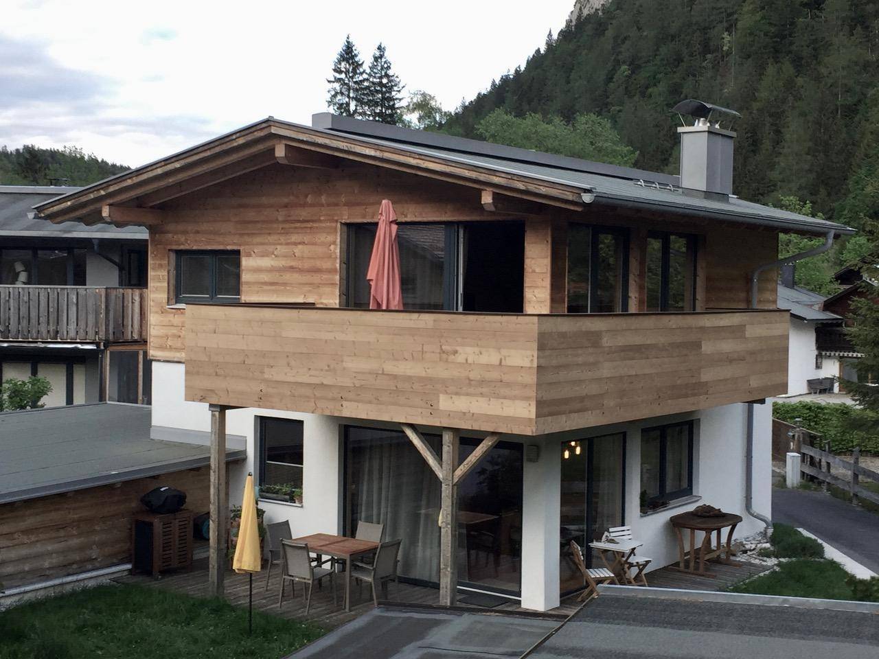 Attraktives Chalet mit Holzbalkon, Terrasse und Blick auf die umliegende Berglandschaft.