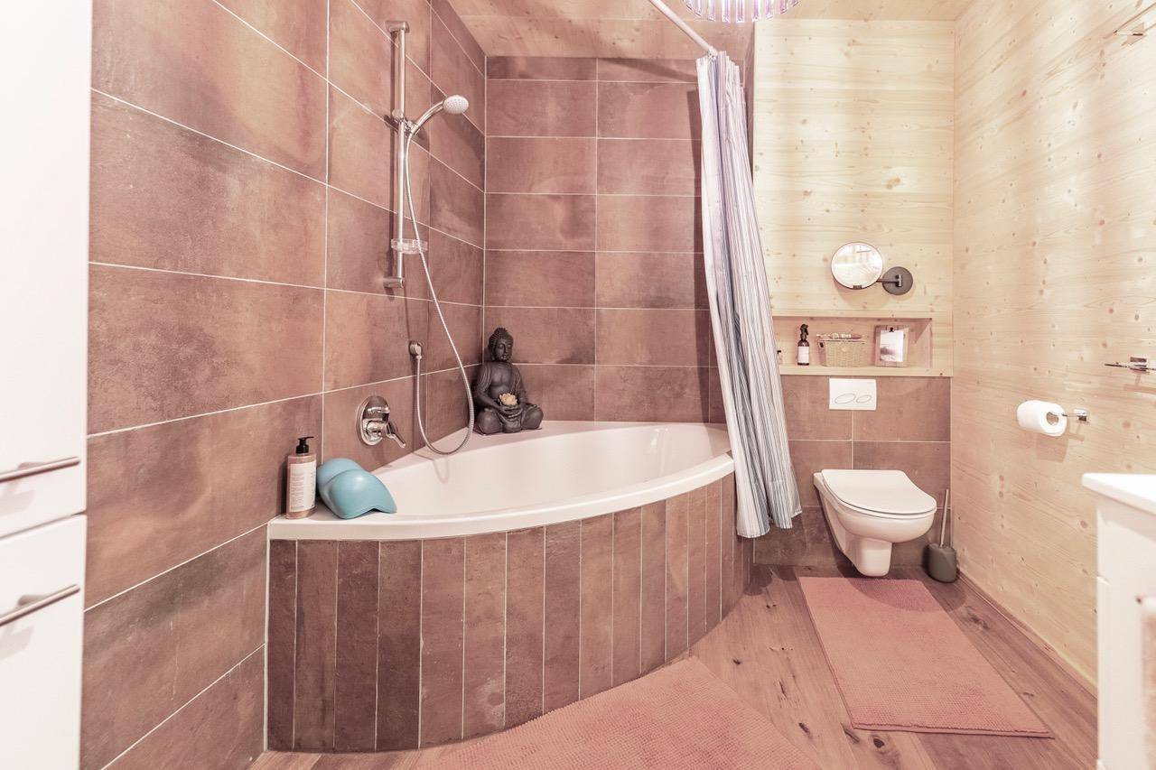 Badezimmer mit Badewanne, Dusche und WC in rustikalem Holzambiente.