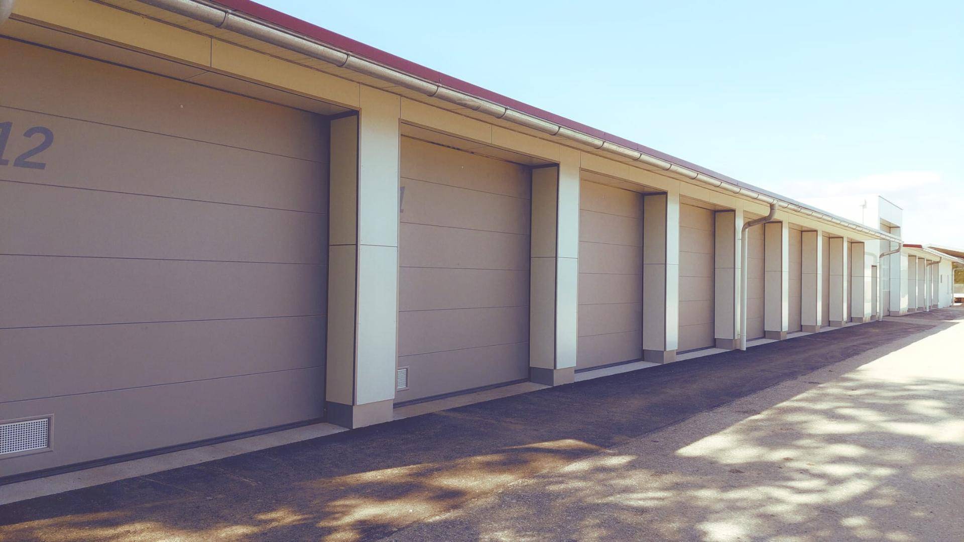 Lange Reihe von Garagenboxen mit individuellen Toren unter hellem Tageslicht.