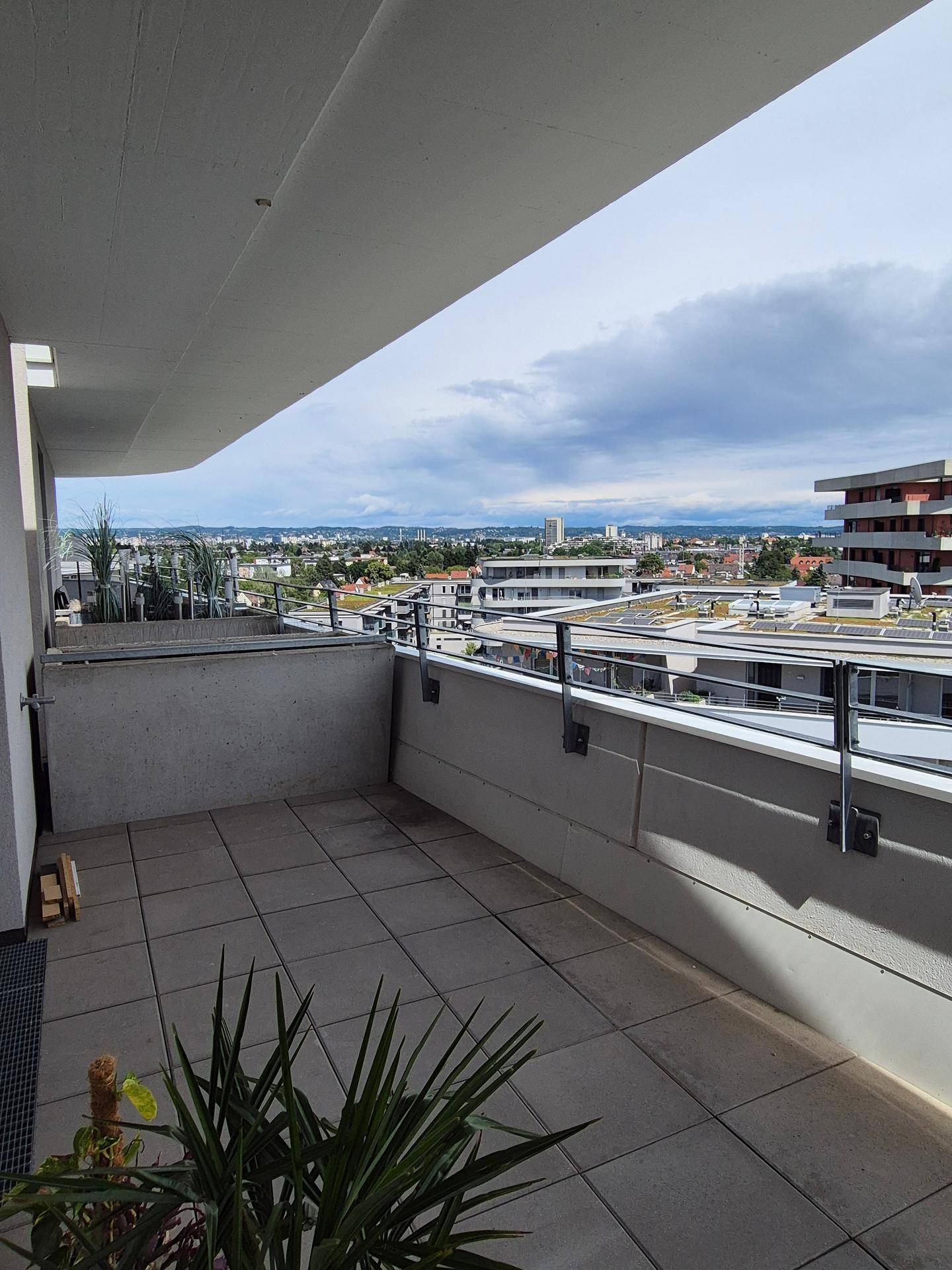 Großer Balkon mit weitem Blick über die moderne Wohnanlage und die umliegende Landschaft.