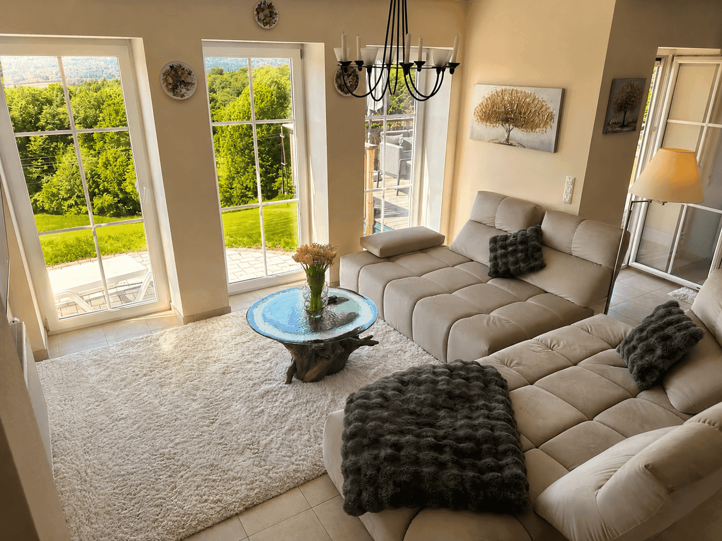 Helles Wohnzimmer mit großem Sofa, Teppich und weitem Blick in die grüne Landschaft.