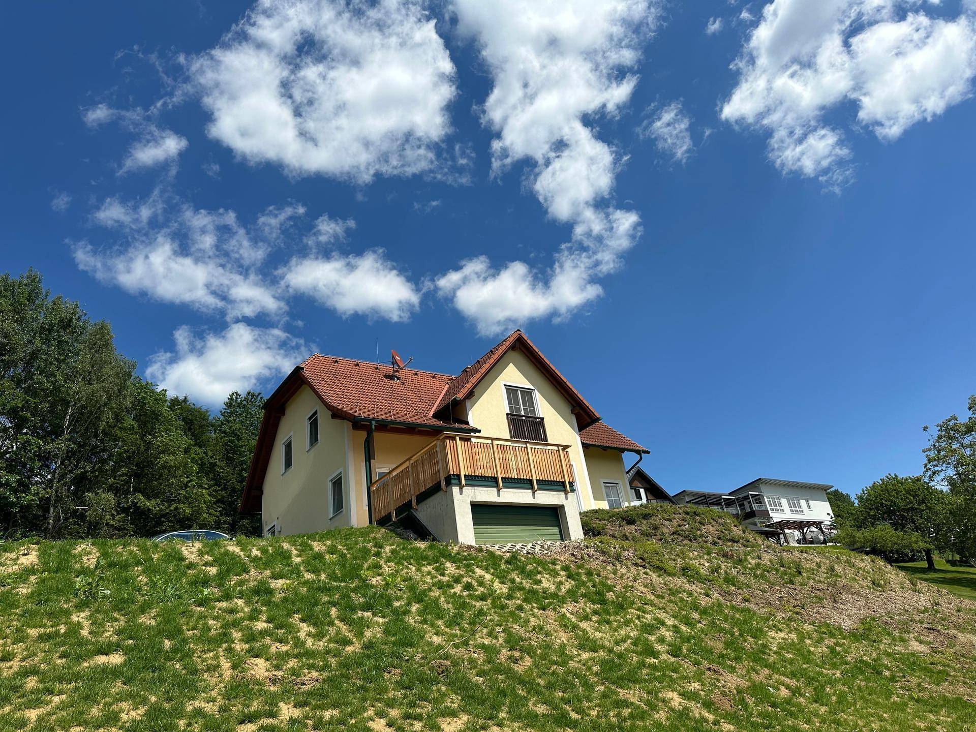 Einfamilienhaus in Hanglage mit traditioneller Architektur und rotem Ziegeldach.