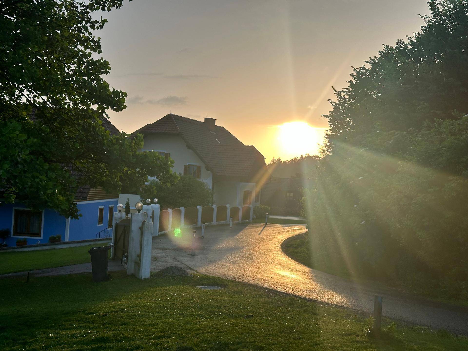 Sonnenuntergang über der ländlichen Umgebung mit einem Haus im Hintergrund.
