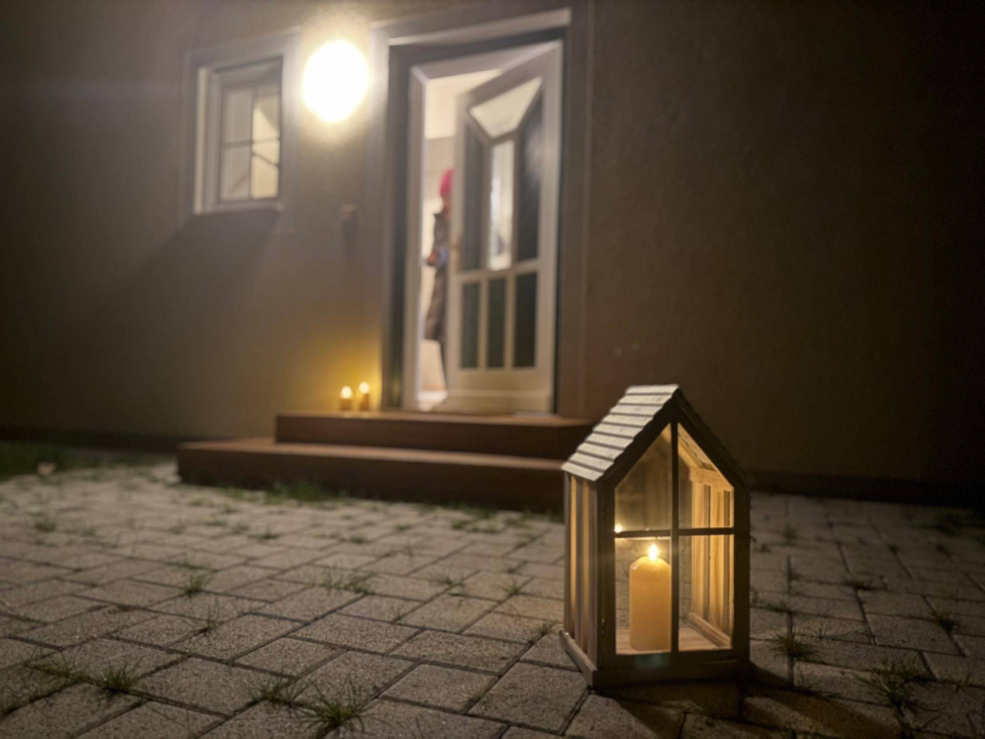 Beleuchteter Eingangsbereich des Hauses bei Nacht mit dekorativen Laternen.