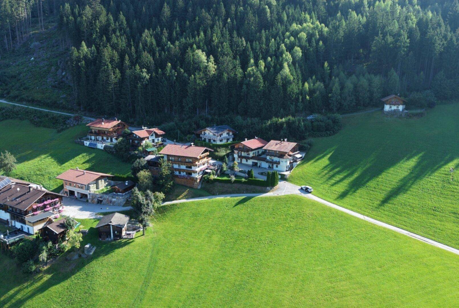 Weitläufige Luftaufnahme einer ländlichen Wohngegend mit viel Grün und Wald.