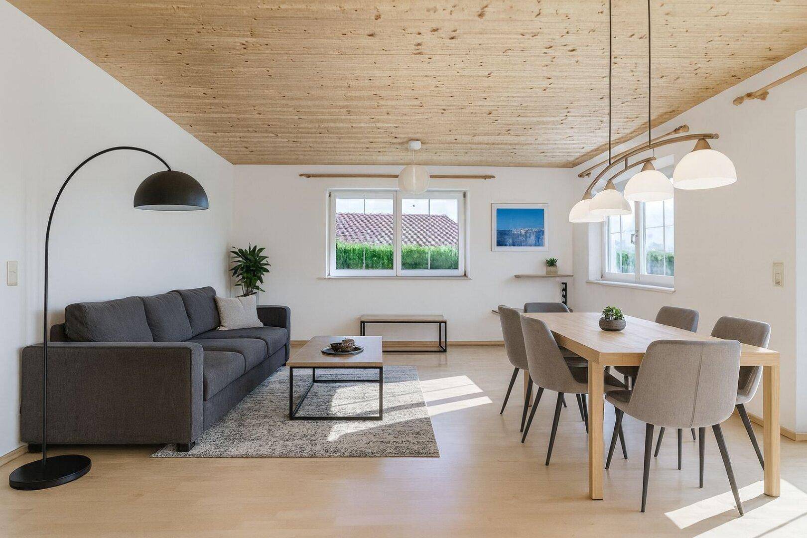 Helles Wohn- und Esszimmer mit Holzbalkendecke, Parkettboden und modernem Mobiliar.