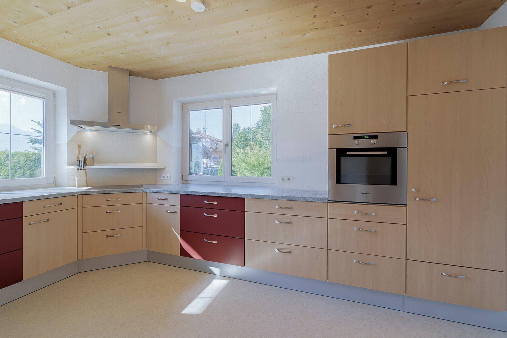 Helle Einbauküche mit Holzfronten, modernen Geräten und viel Tageslicht.