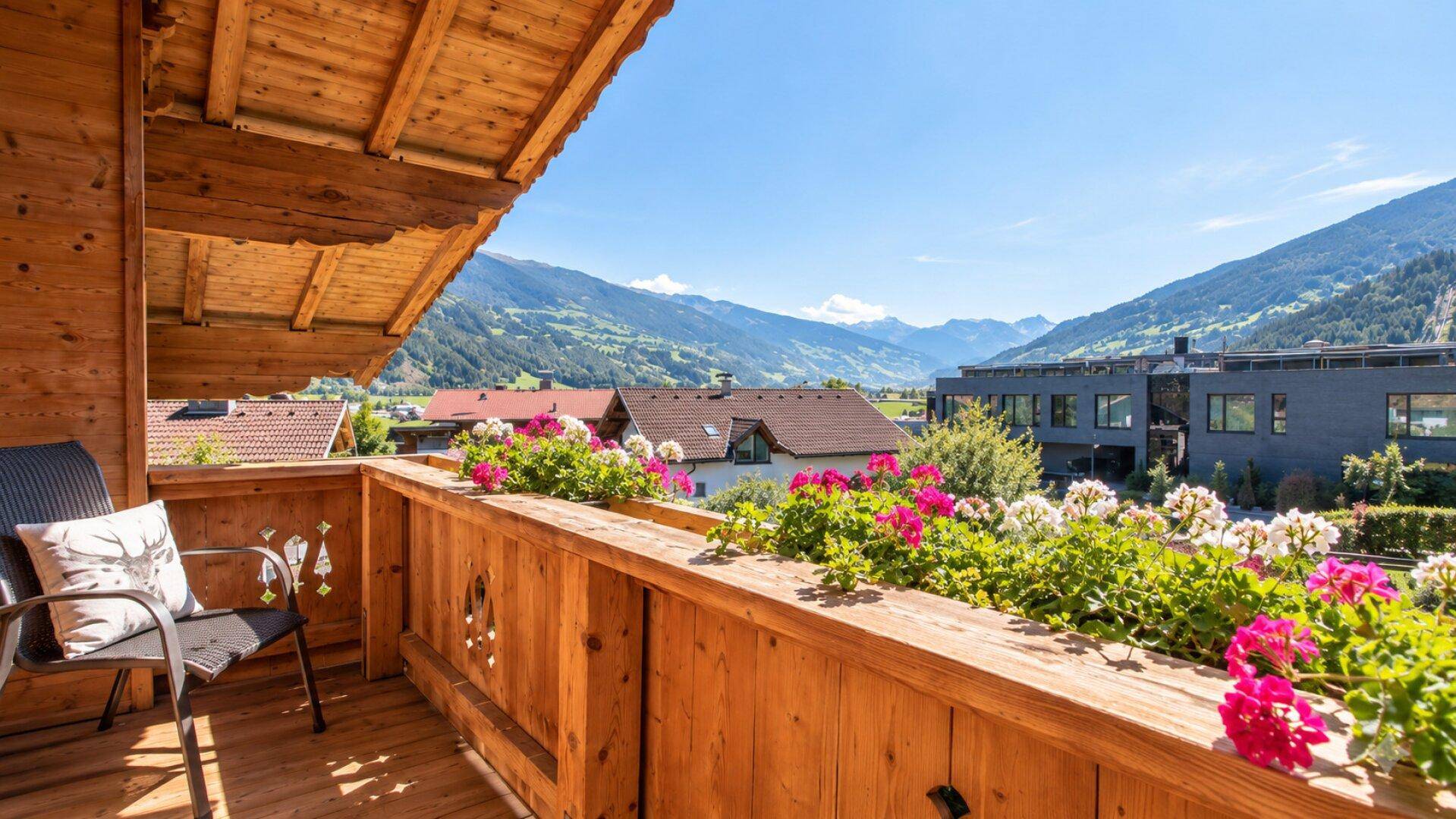 Sonniger Balkon mit Blumenkästen und weitem Blick auf die umliegende Berglandschaft.