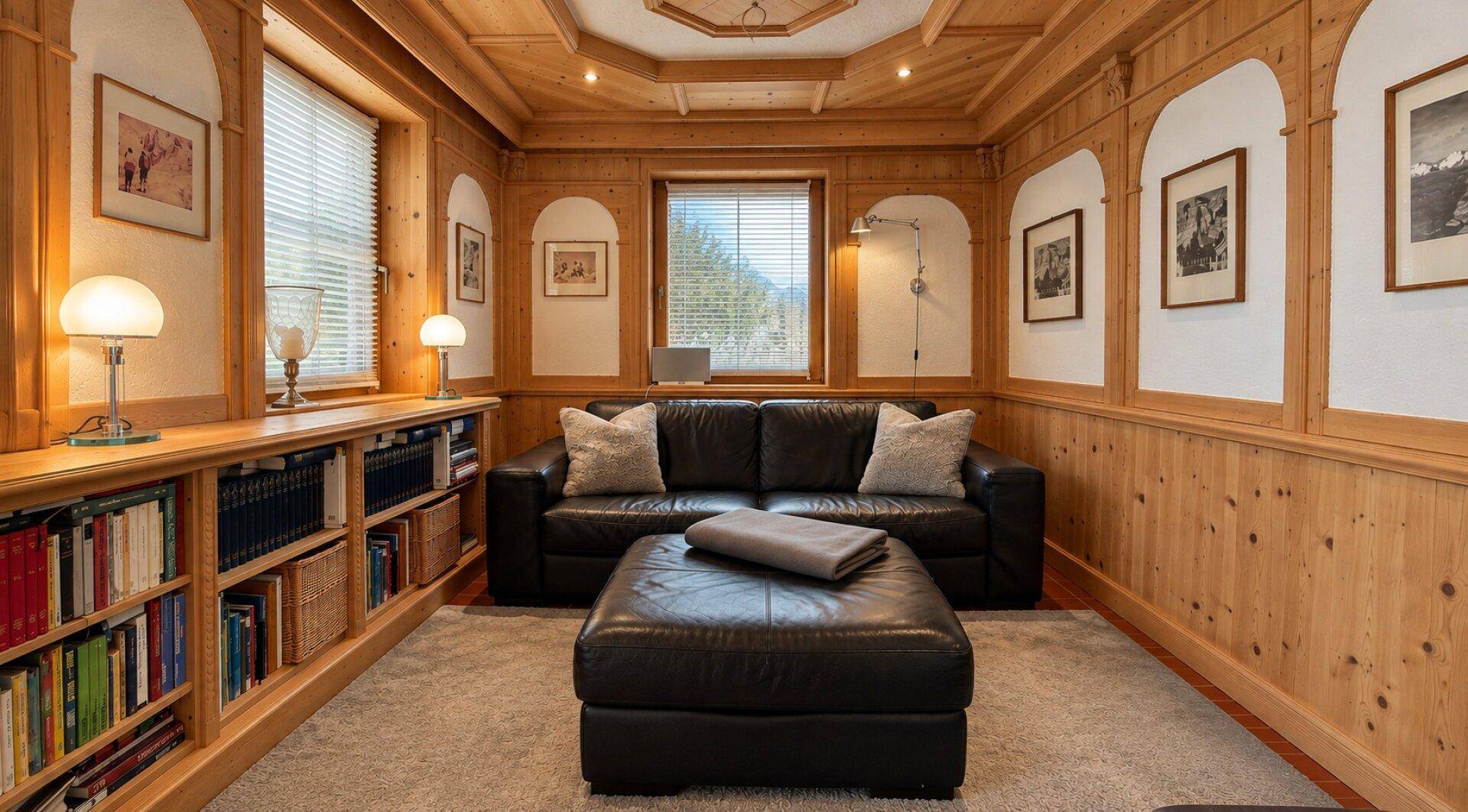 Rustikales Wohnzimmer mit Holztäfelung, Ledersofa und integrierten Bücherregalen.