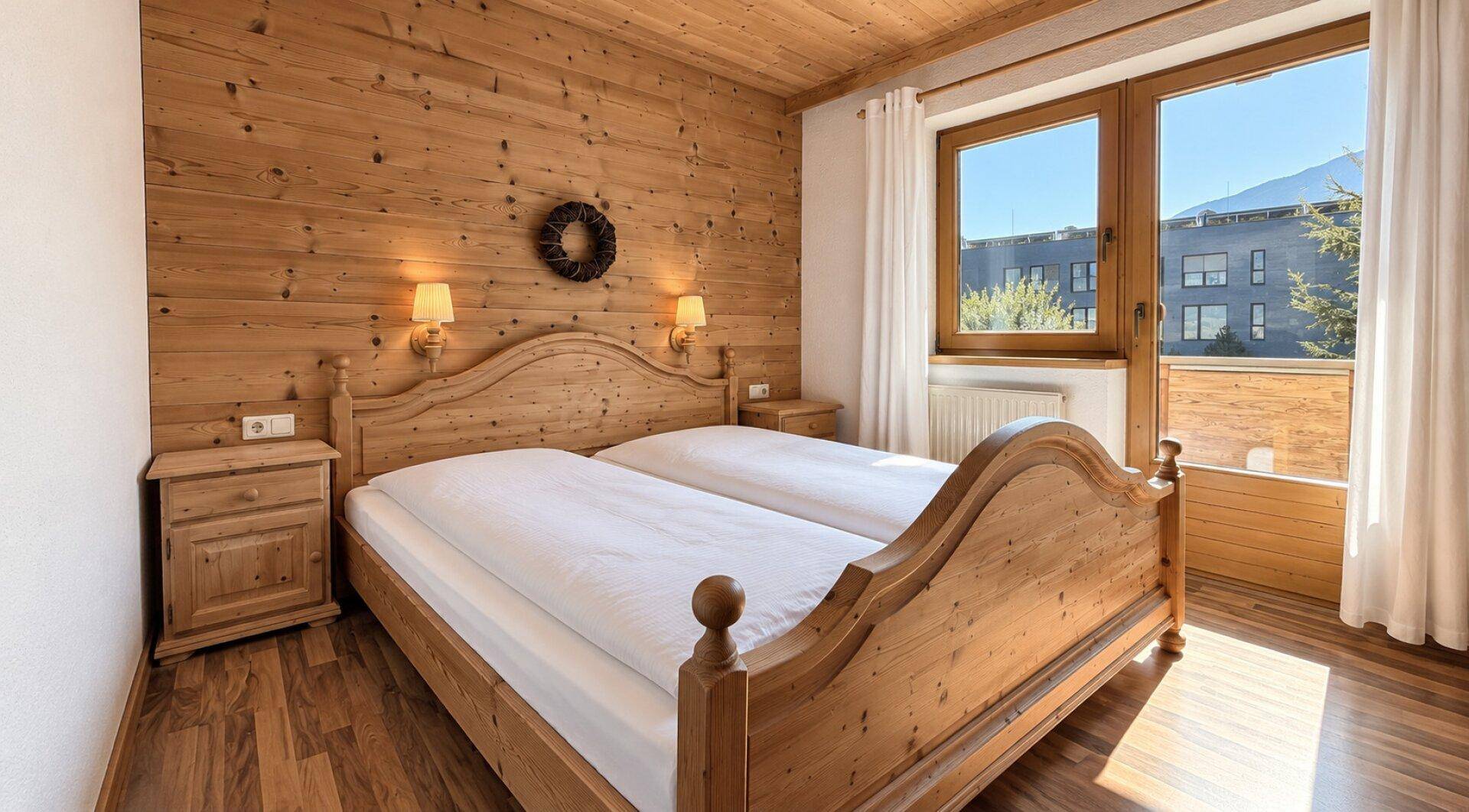 Schlafzimmer im Landhausstil mit Holzdoppelbett, Holzwänden und Balkonzugang.