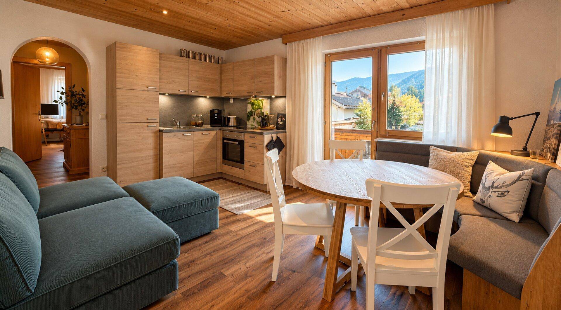 Offener Wohn-Essbereich mit moderner Küchenzeile, Esstisch und Sofa, mit Bergblick.