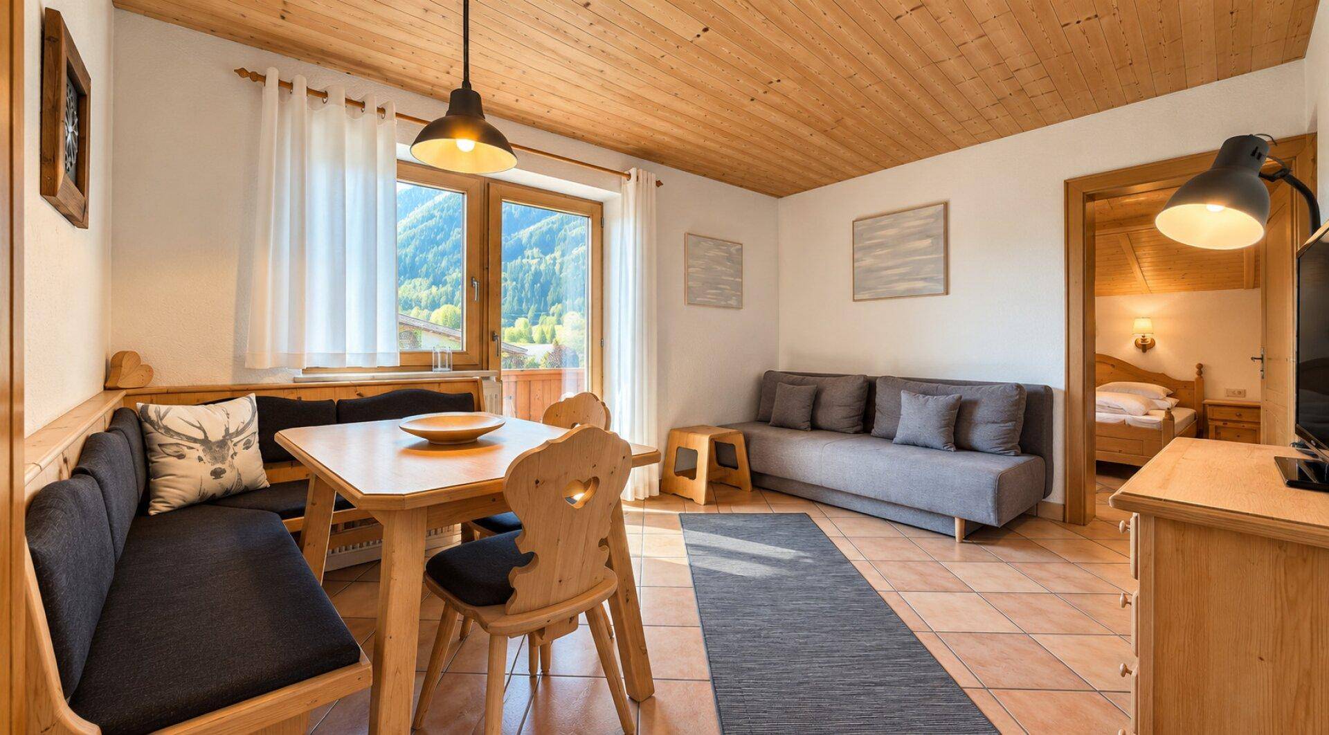Heller Wohn- und Essbereich mit Sofa, Esstisch und Zugang zu einem weiteren Schlafzimmer.