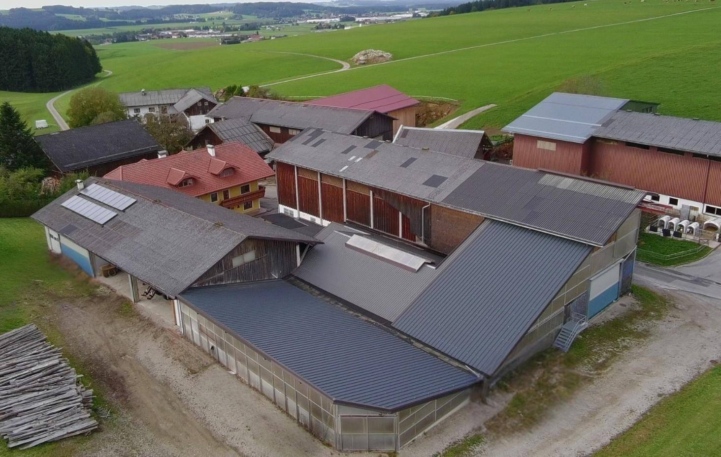 Luftaufnahme eines landwirtschaftlichen Anwesens mit mehreren Gebäuden und grünen Feldern in ländlicher Umgebung.