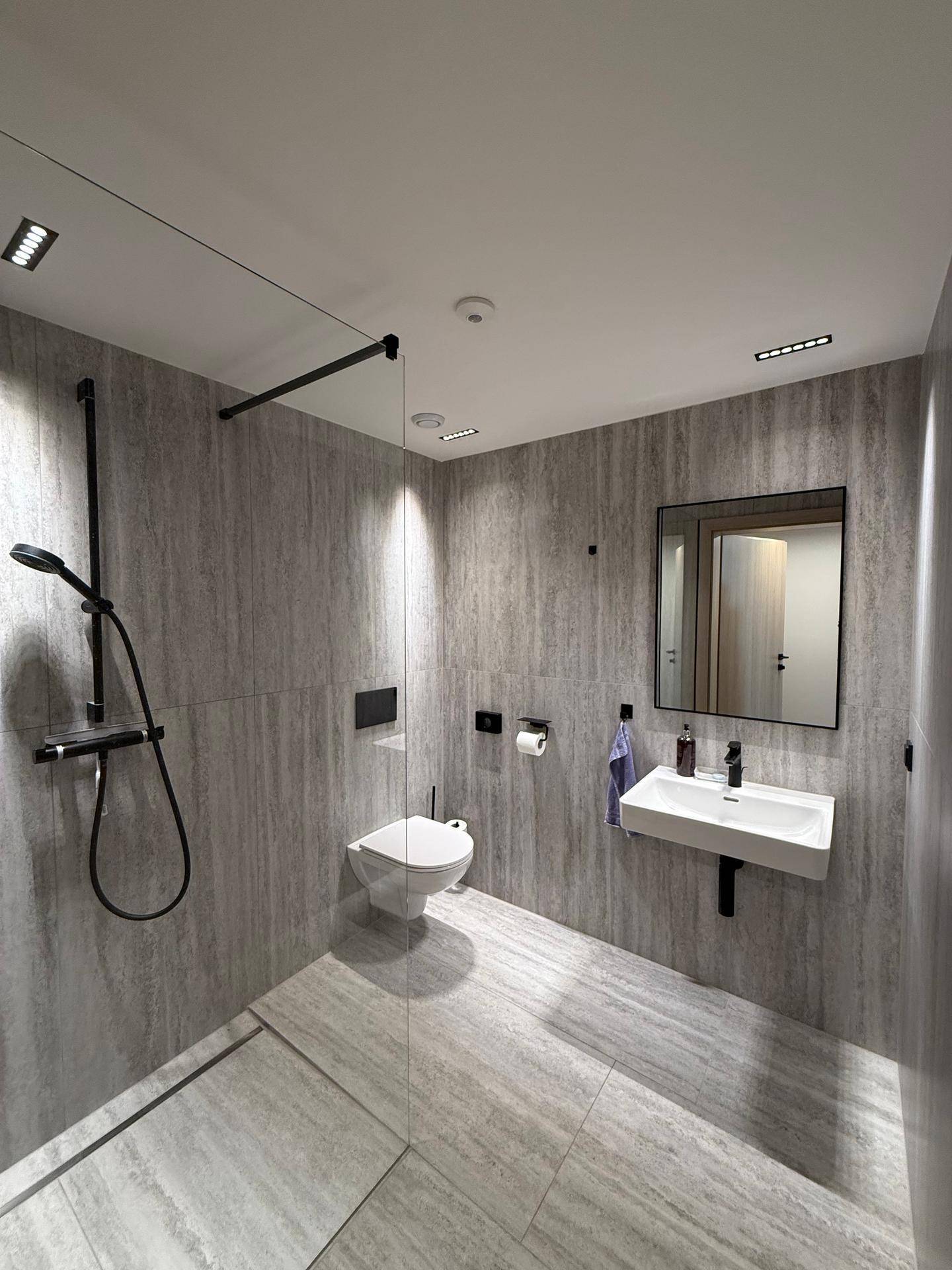 Modernes Badezimmer mit großer begehbarer Dusche, Wand-WC und eleganten Fliesen.