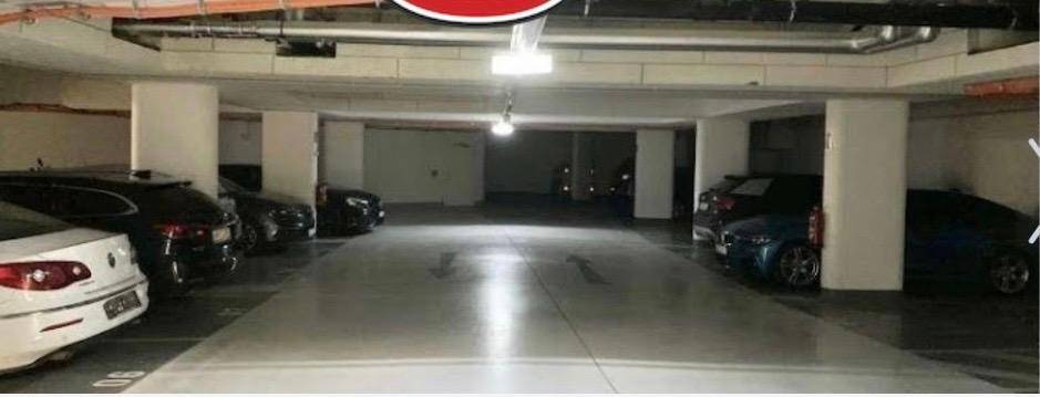 Geräumige Tiefgarage mit mehreren Parkplätzen, Säulen und guter künstlicher Beleuchtung.