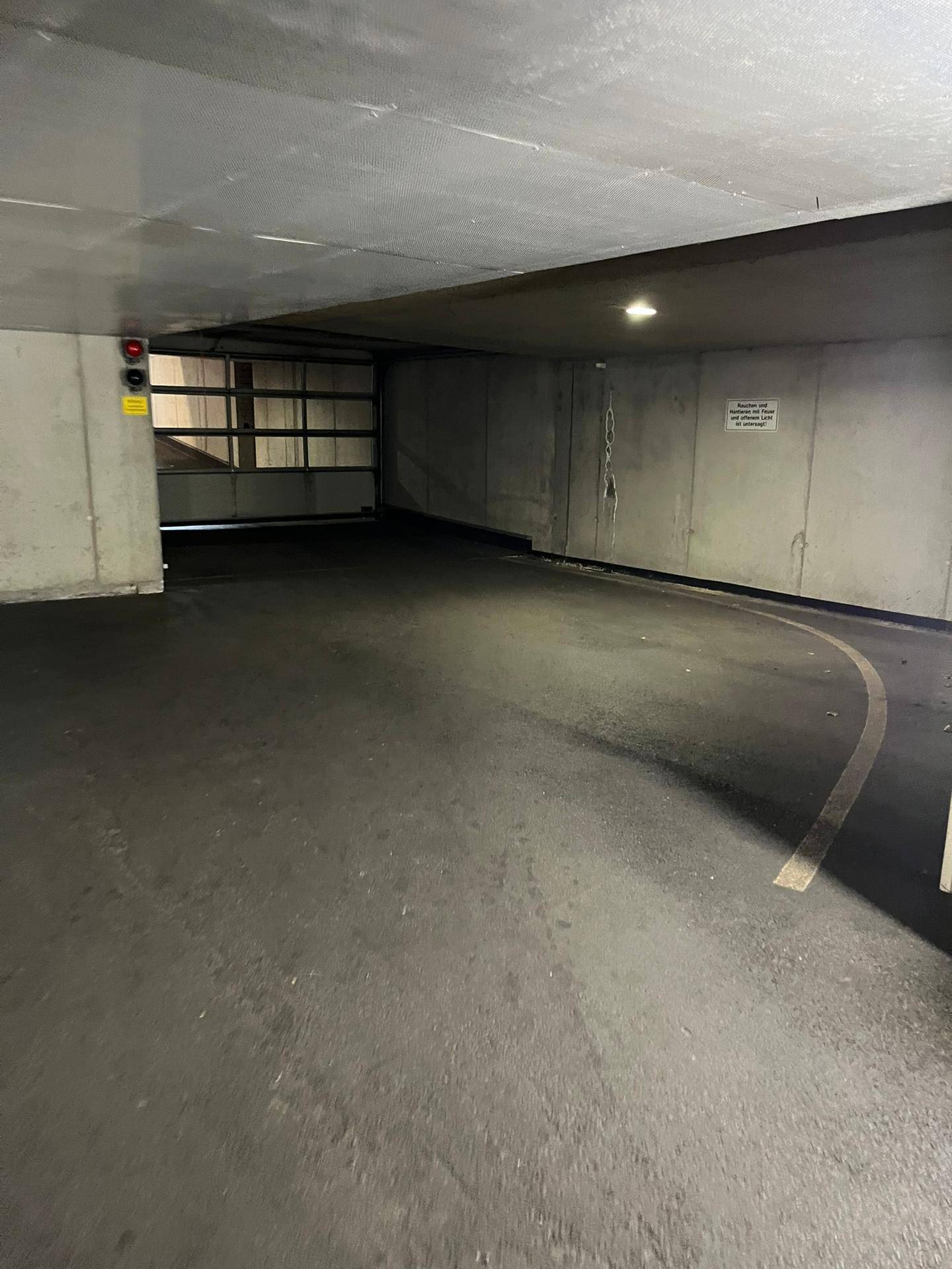 Zufahrt zur Tiefgarage mit Betonwänden und dunklem Bodenbelag.