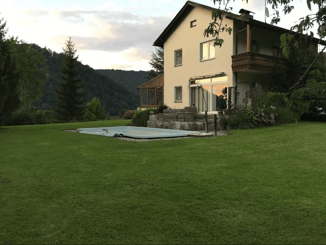 Großer Garten mit Rasenfläche und Pool neben dem Wohnhaus in ländlicher Umgebung.