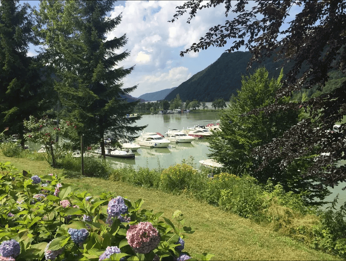 Panoramablick auf den See mit Bootsanlegestellen und umliegende Berglandschaft.
