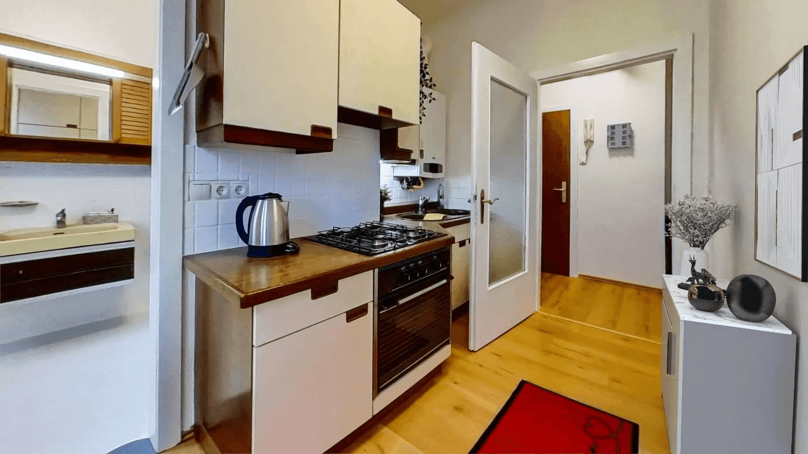 Funktionale Küche mit Gasherd, Backofen und Holztheke, angrenzend an einen Flur.