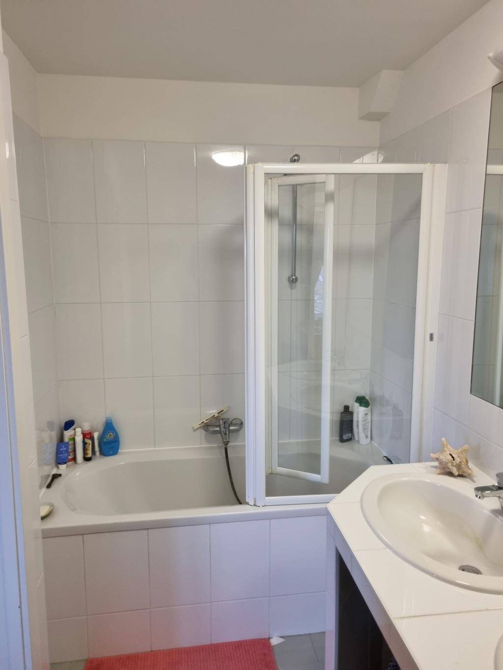 Helles Badezimmer mit Badewanne, Duschabtrennung und weiß gefliesten Wänden.