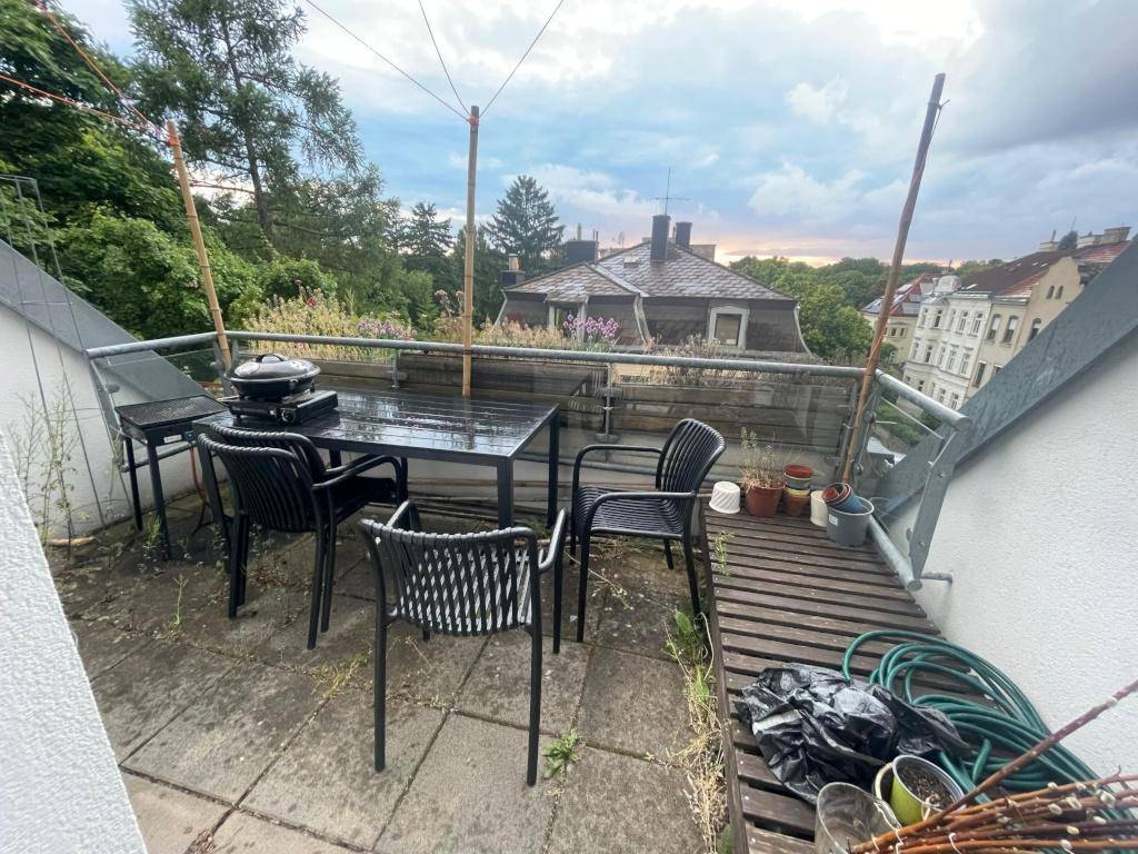 Dachterrasse mit Gartenmöbeln, Grill und Blick über die Dächer der Stadt.