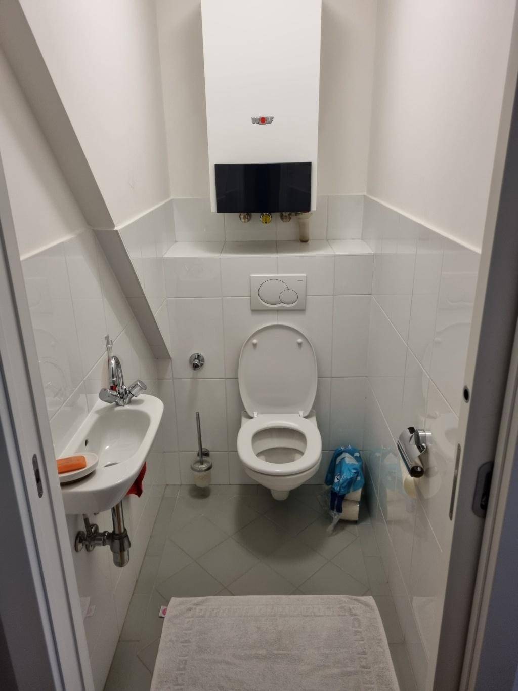 Kleines Gäste-WC mit Wand-WC, Handwaschbecken und Gastherme.