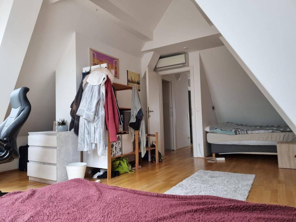 Dachzimmer mit Holzboden, Klimaanlage und Blick auf den angrenzenden Flur.