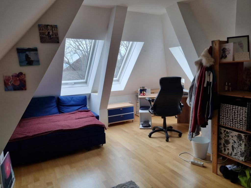 Geräumiges Dachzimmer mit Schreibtisch, Bett und viel Tageslicht durch die Dachfenster.