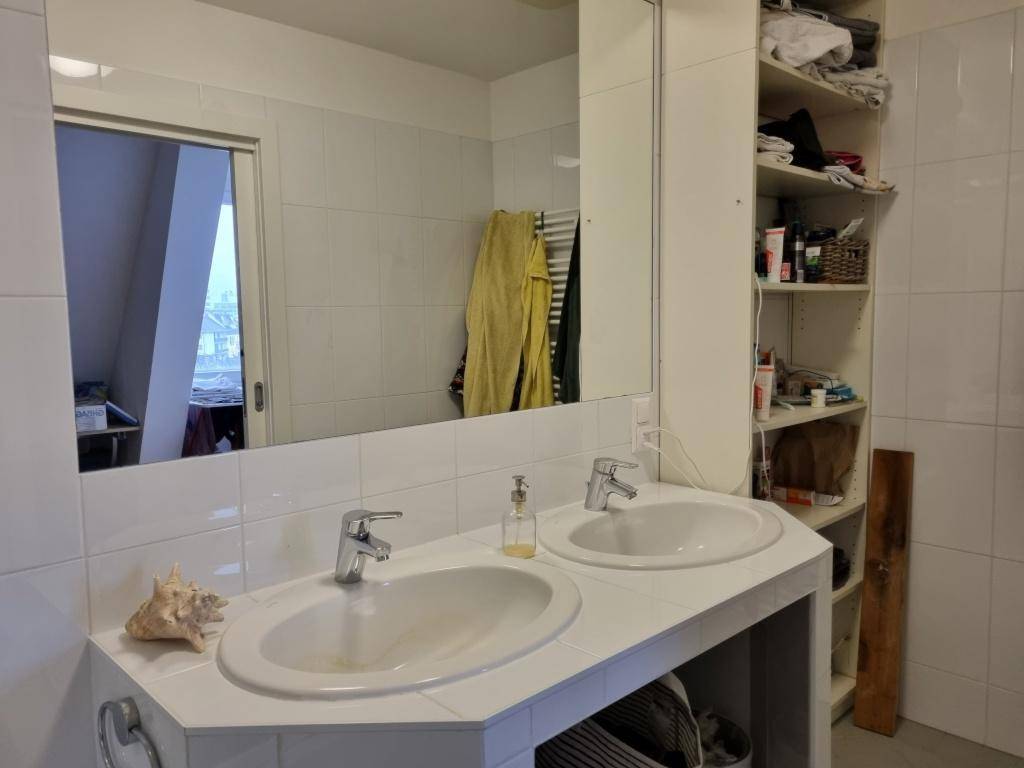 Badezimmer mit Doppelwaschbecken, großem Spiegel und praktischen Ablagen.