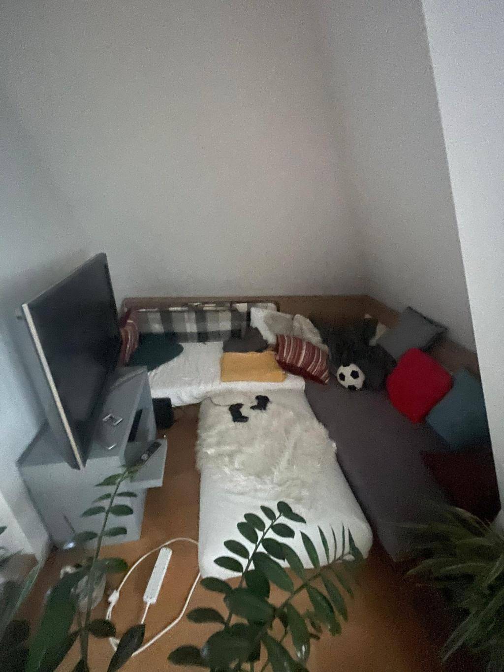 Gemütliche Sitzecke im Dachgeschoss mit Fernseher und weichen Kissen.