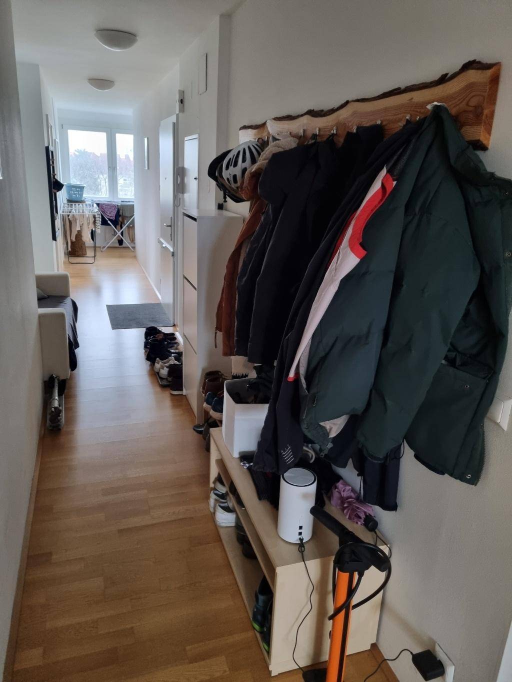 Langer Flur mit Holzboden, Garderobe und Blick in den hinteren Bereich der Wohnung.