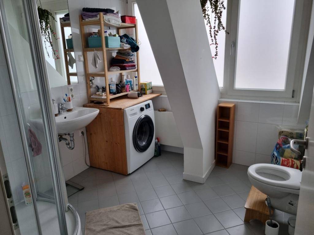 Badezimmer im Dachgeschoss mit Dusche, WC, Waschmaschine und Dachfenster.
