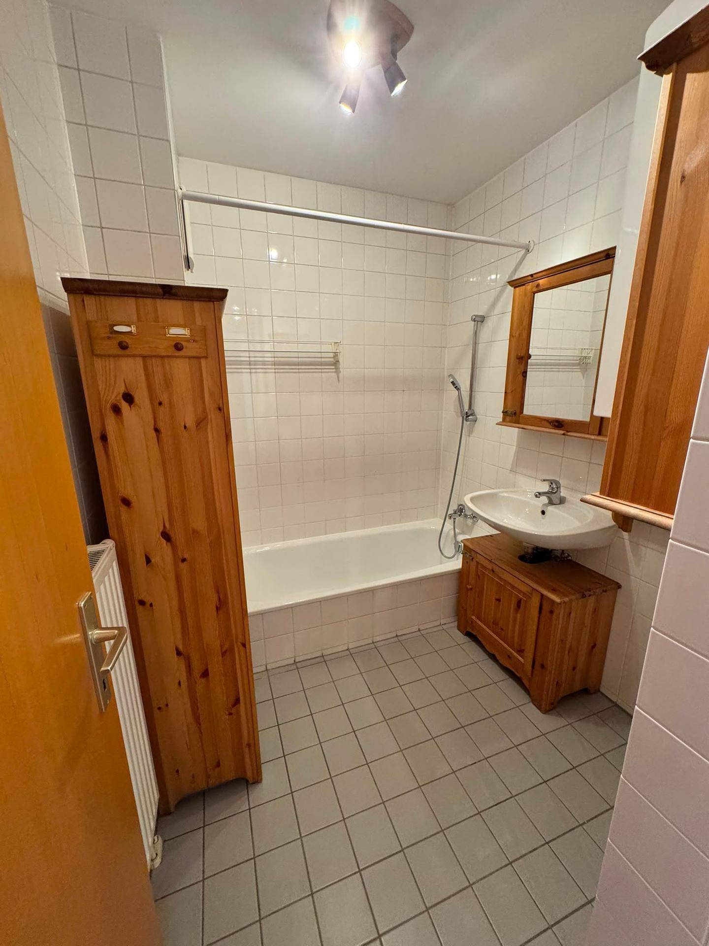 Badezimmer mit Badewanne, Waschbecken und Holzmöbeln im traditionellen Stil.