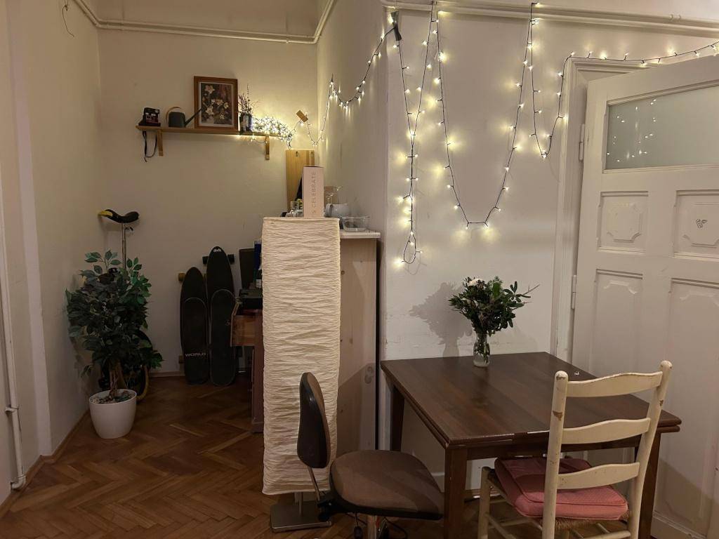 Gemütlicher Essbereich mit Holztisch, Stühlen und dekorativer Lichterkette.