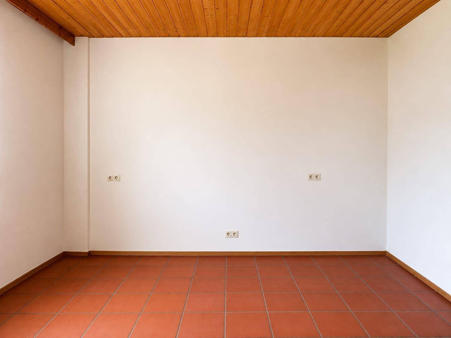 Leerer Raum mit Terrakottafliesen und Holzdecke, bereit zur individuellen Gestaltung.