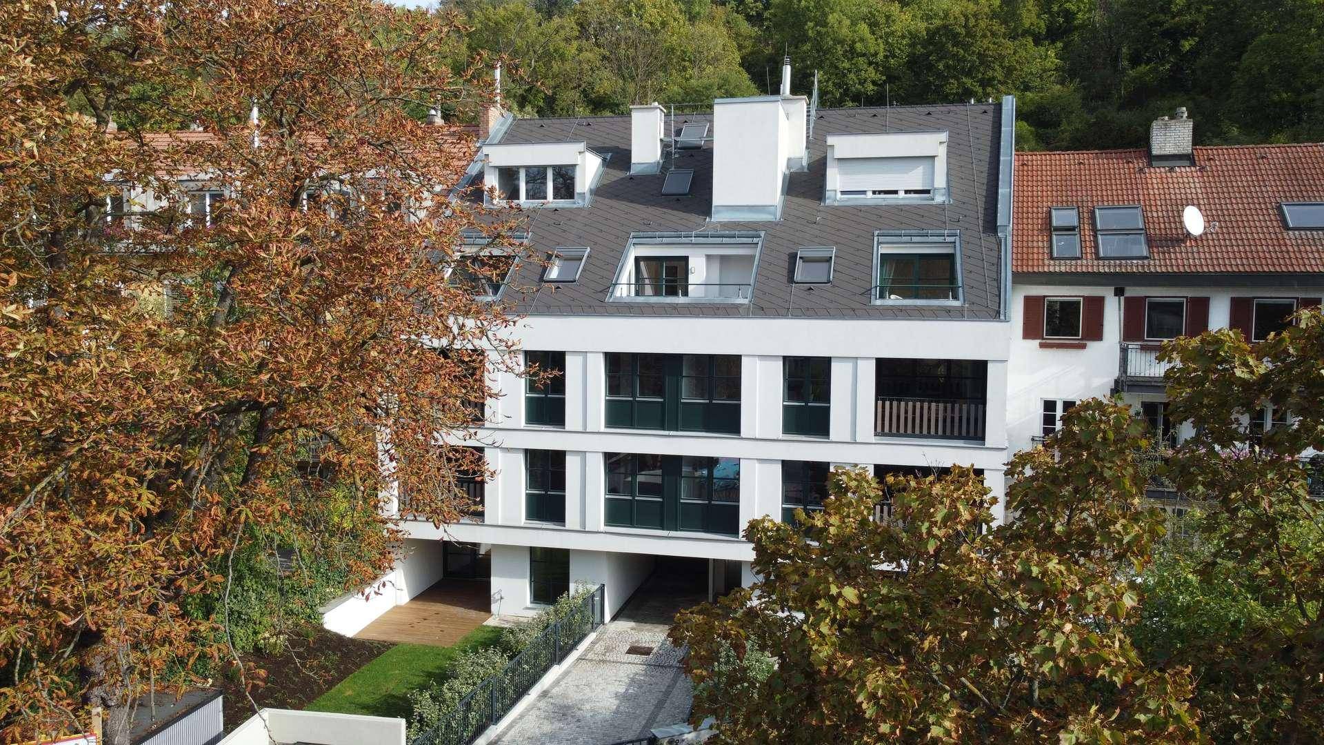 Moderne Wohnanlage mit mehreren Etagen, Balkonen und umgebenden Bäumen.