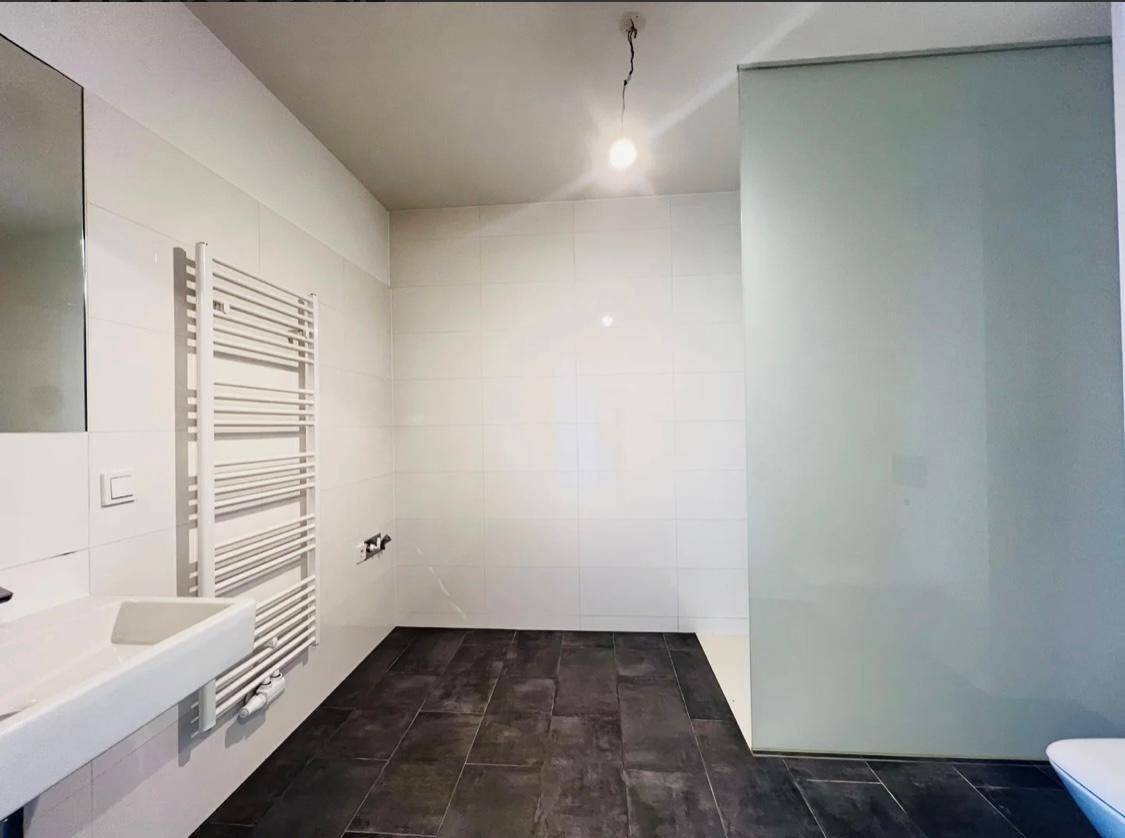 Helles Badezimmer mit modernem Design, Dusche und praktischem Handtuchheizkörper.