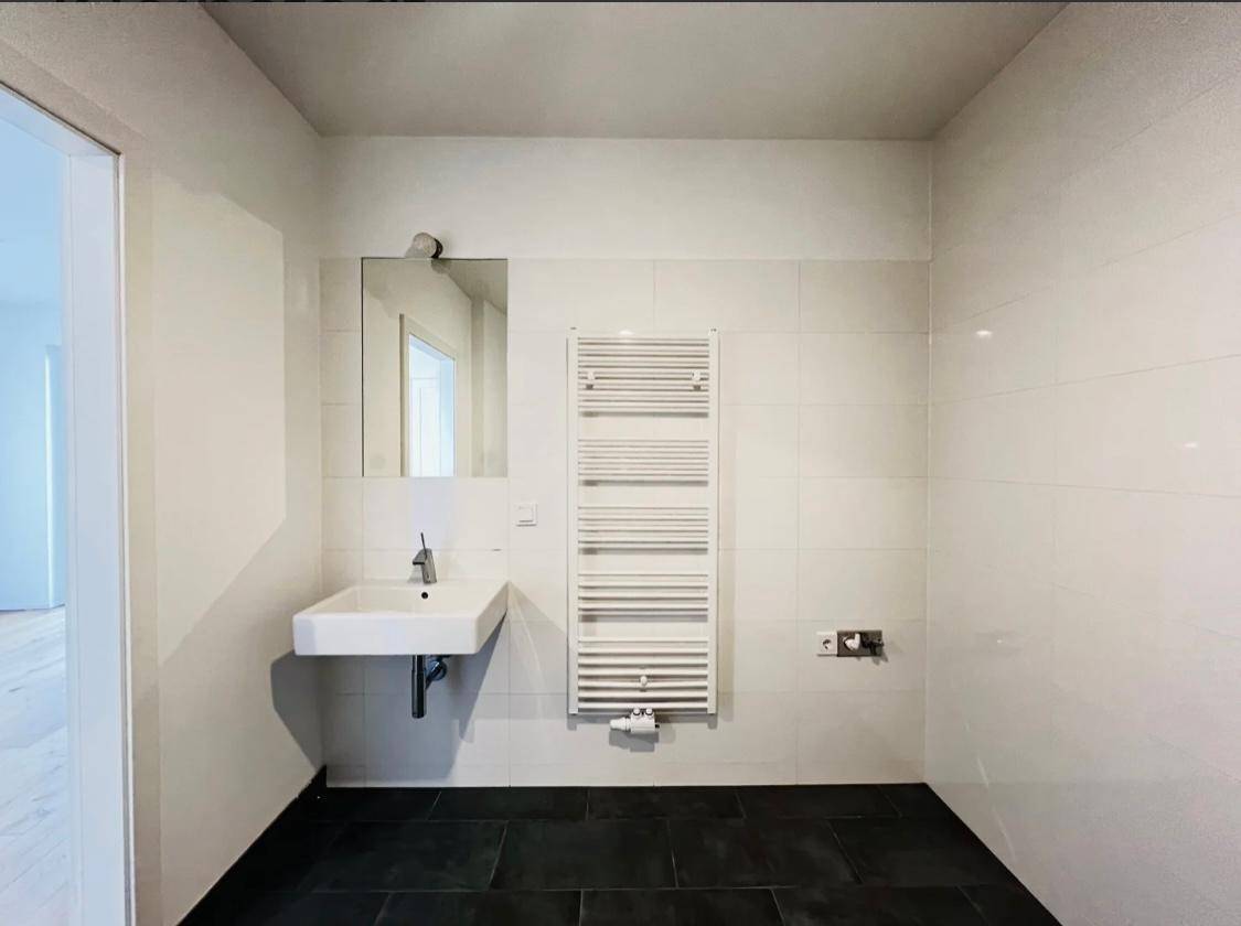 Modernes Badezimmer mit Einzelwaschbecken, Spiegel und beheiztem Handtuchhalter.