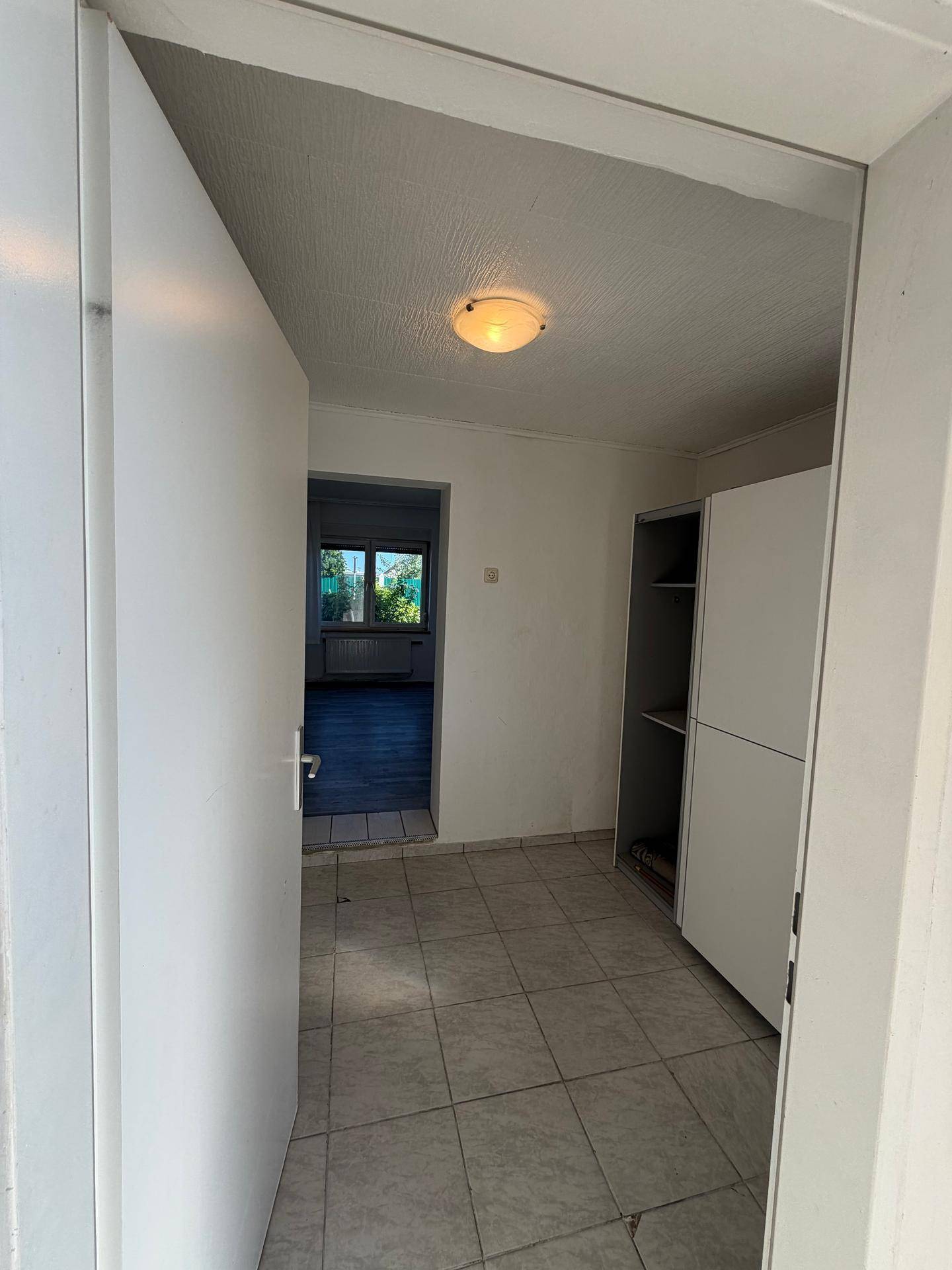 Eingangsbereich mit Fliesenboden und praktischem Einbauschrank, führt in weitere Räume.
