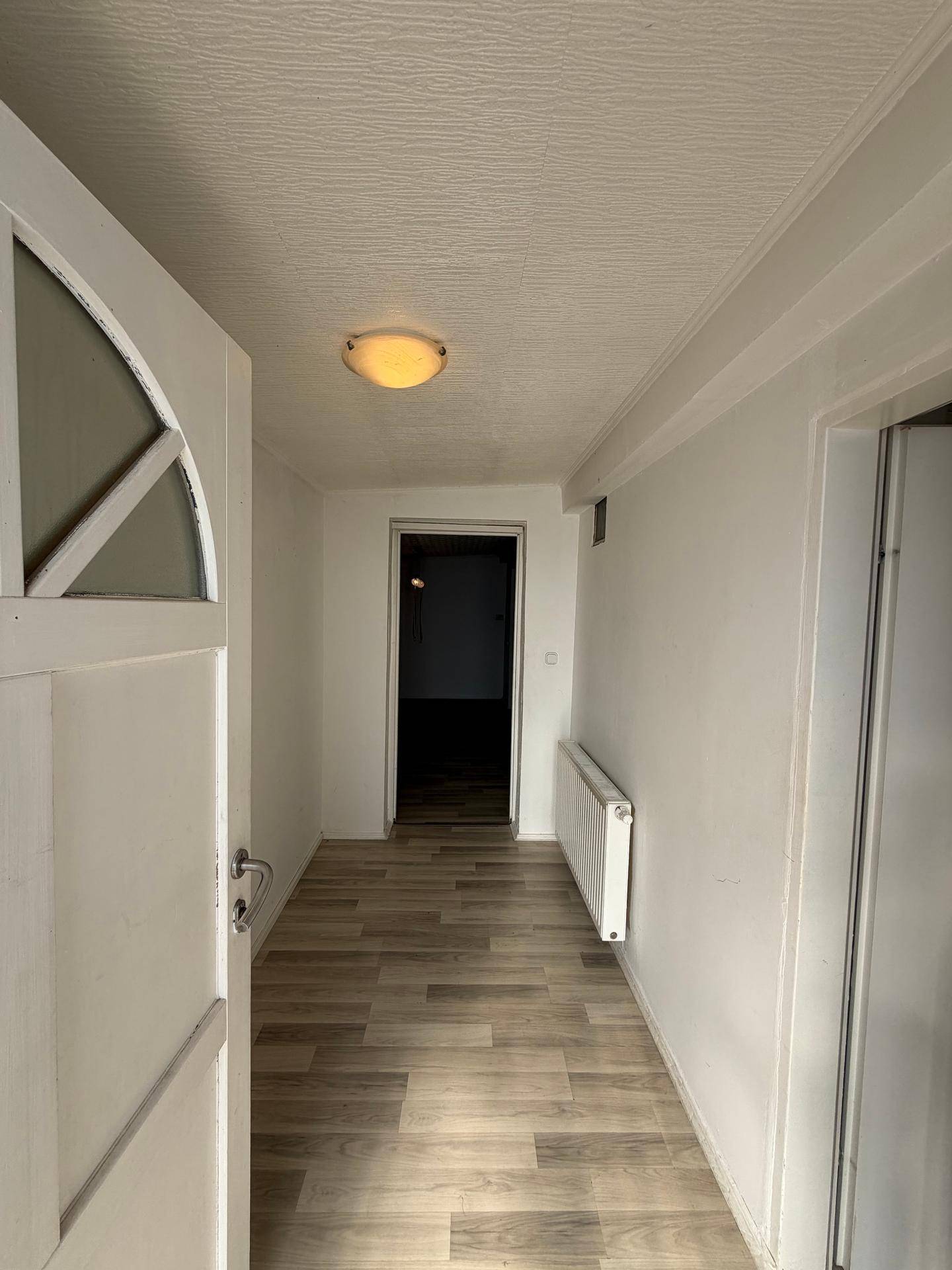 Heller Flur mit Laminatboden und Zugang zu weiteren Räumen im Haus.