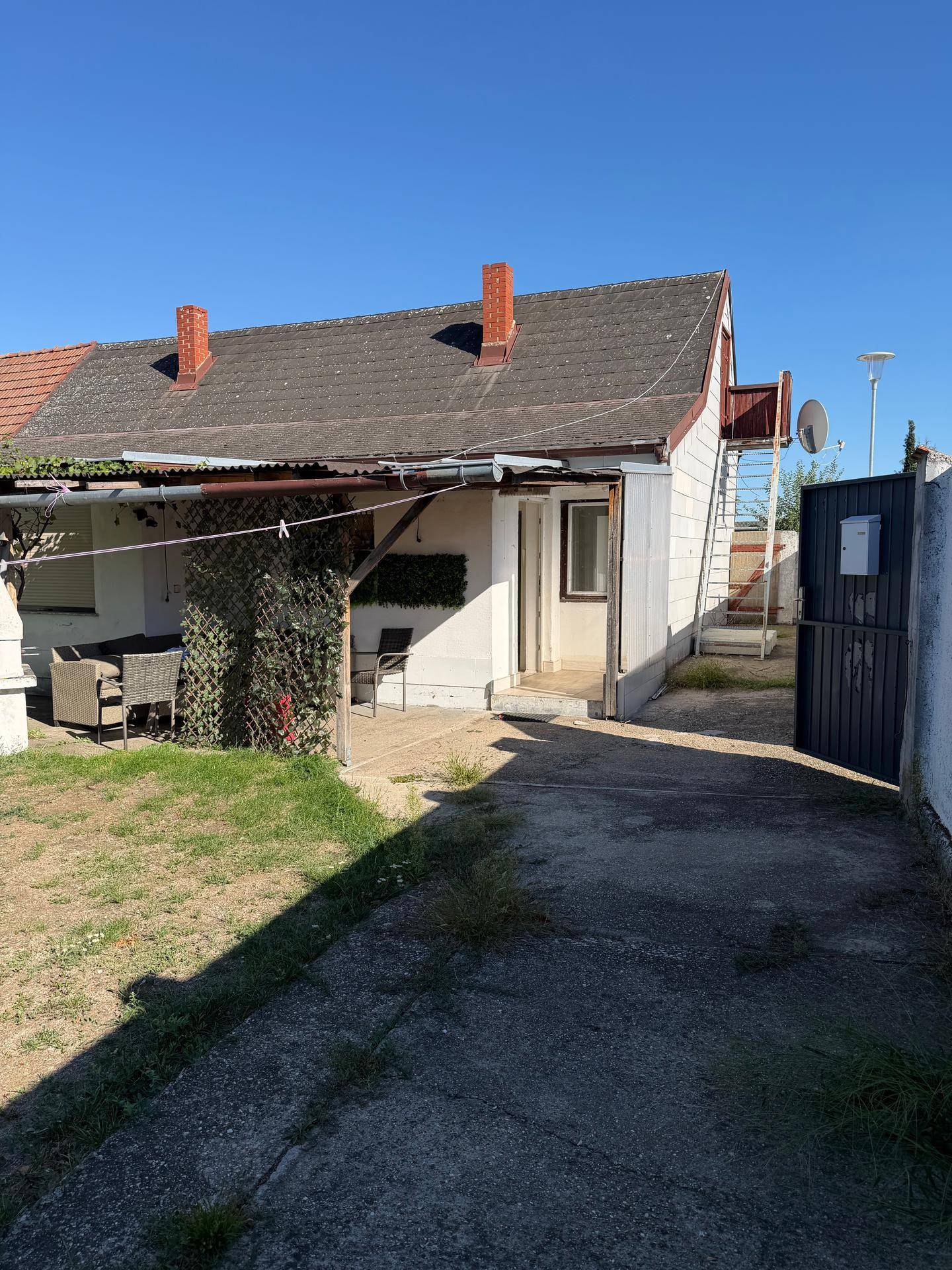 Rückansicht des Hauses mit überdachtem Bereich und Zugang zum Garten.