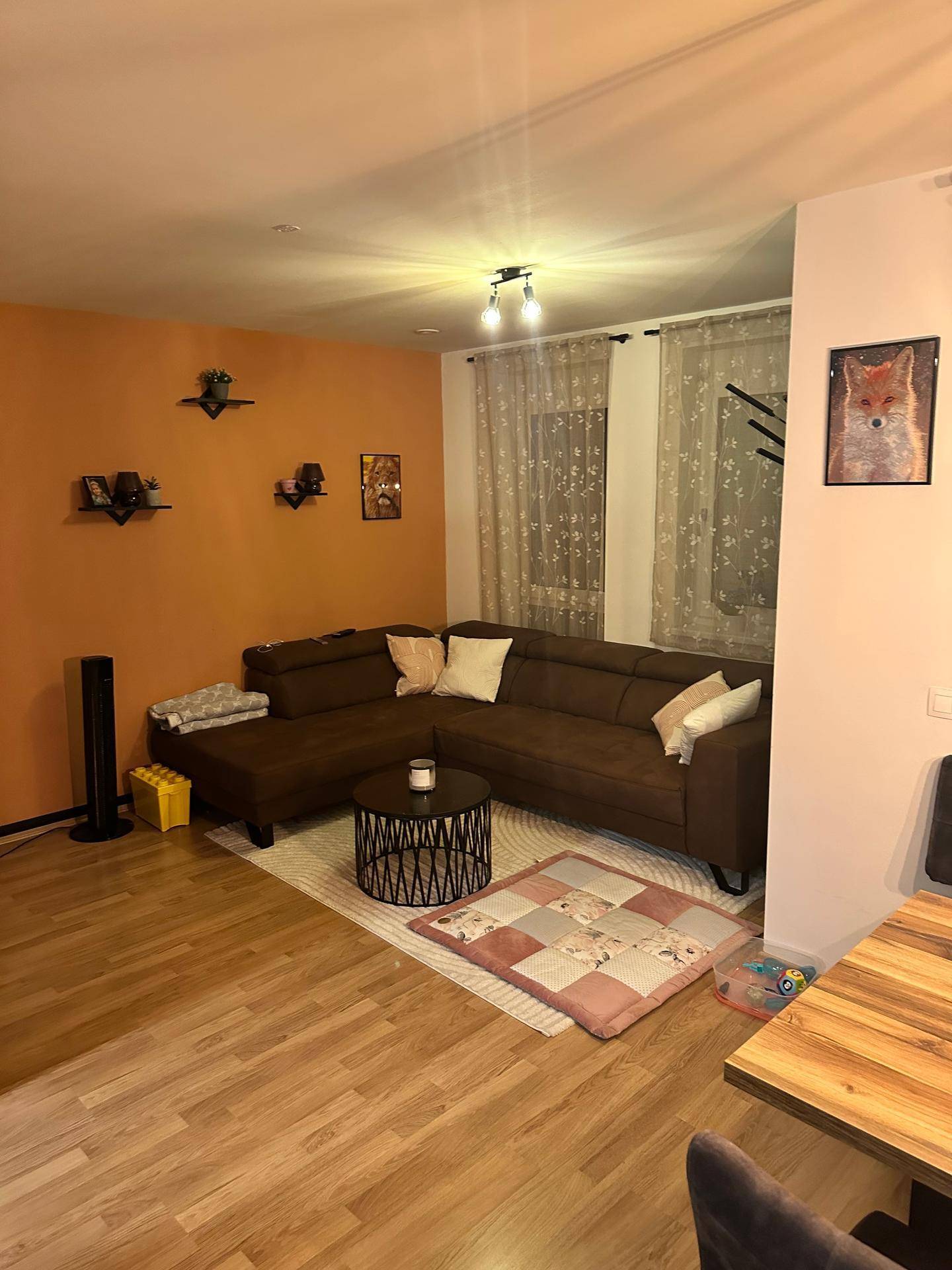 Gemütlicher offener Wohn- und Essbereich mit Ecksofa, Holztisch und Laminatboden.