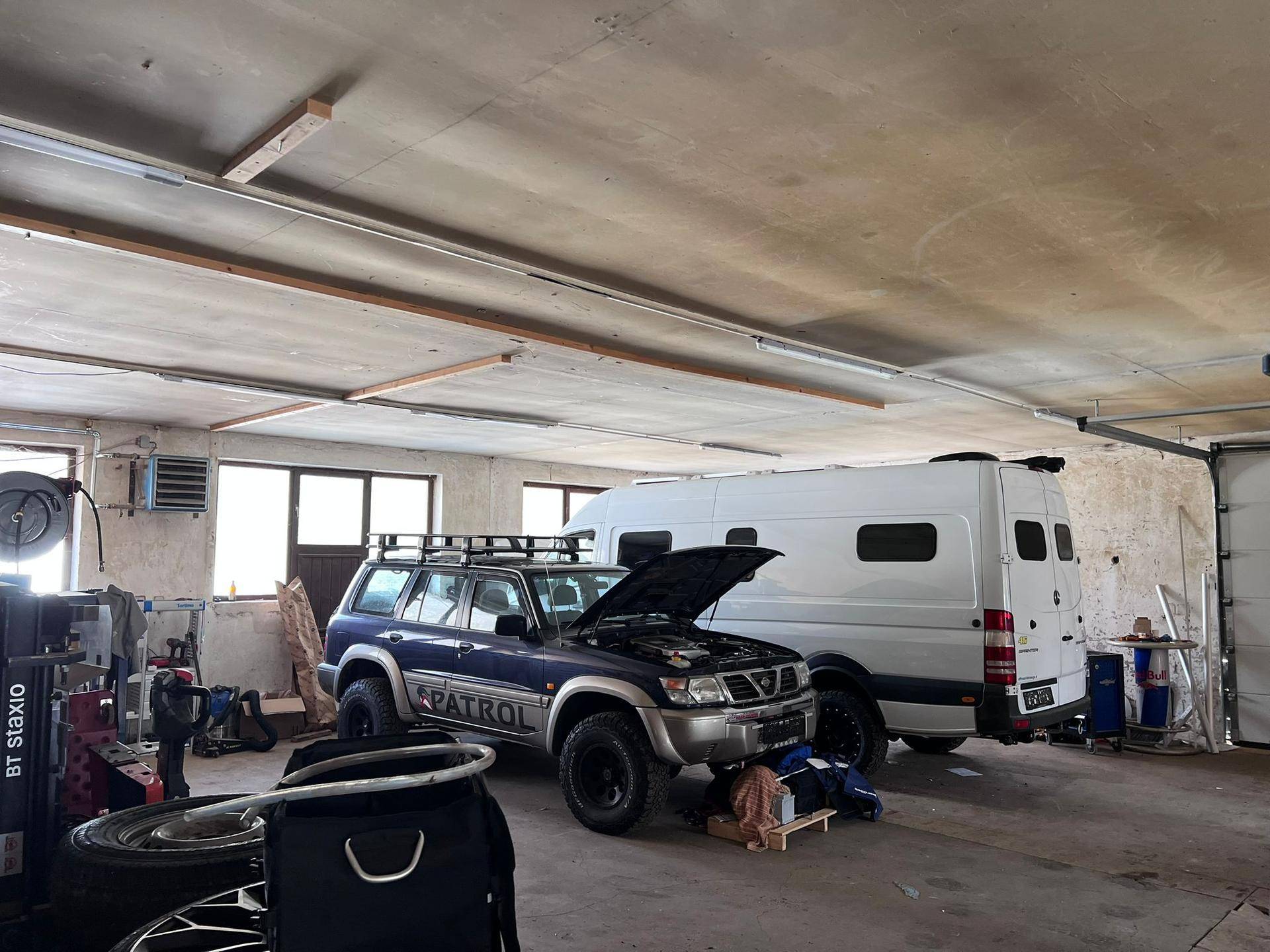 Geräumige Garage mit einem blauen SUV und einem weißen Transporter, bereit für Wartung oder Lagerung.