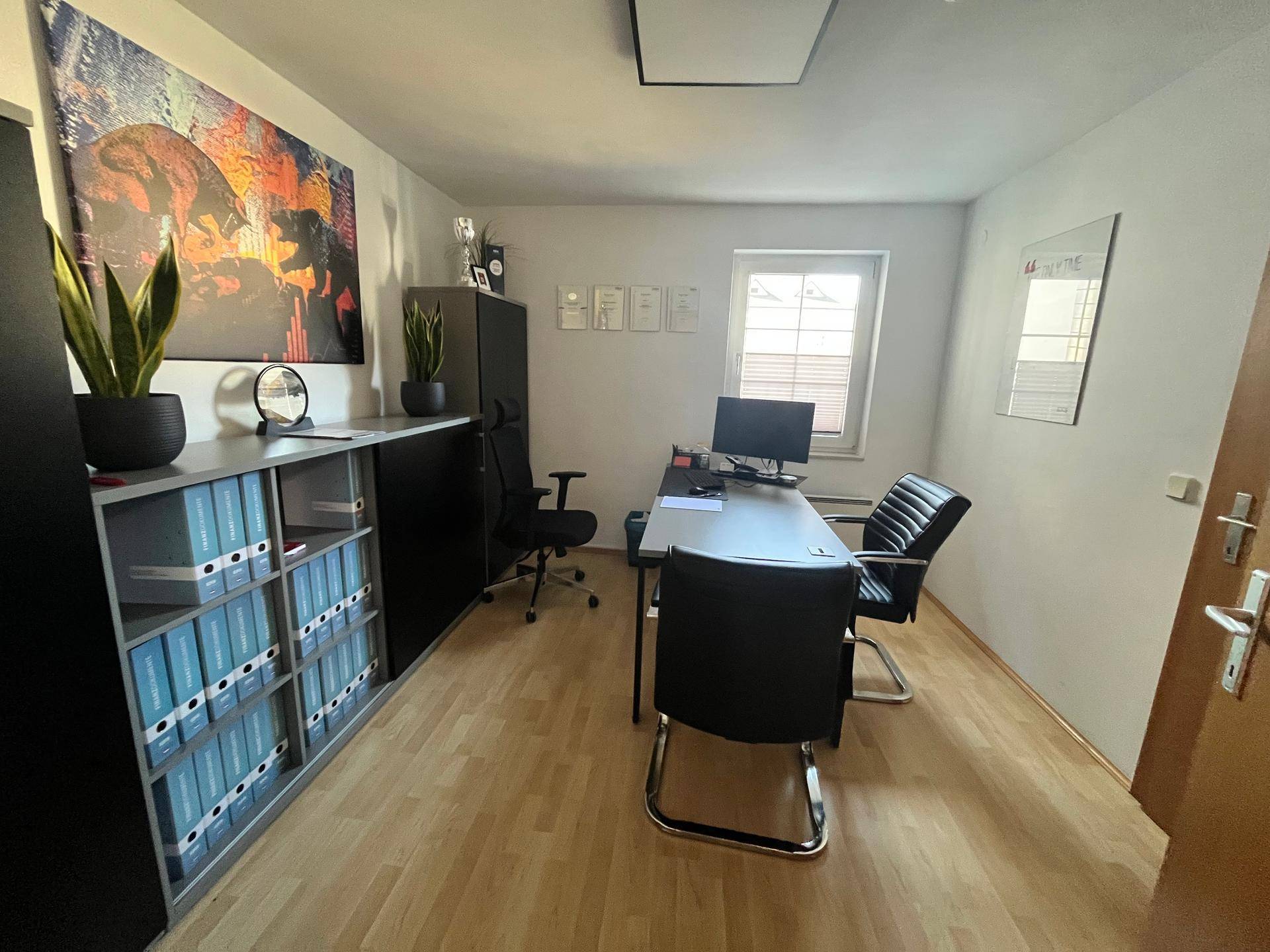 Geräumiges Büro mit Parkettboden, Schreibtisch, Bürostühlen und Regalen für Akten und Dekoration.