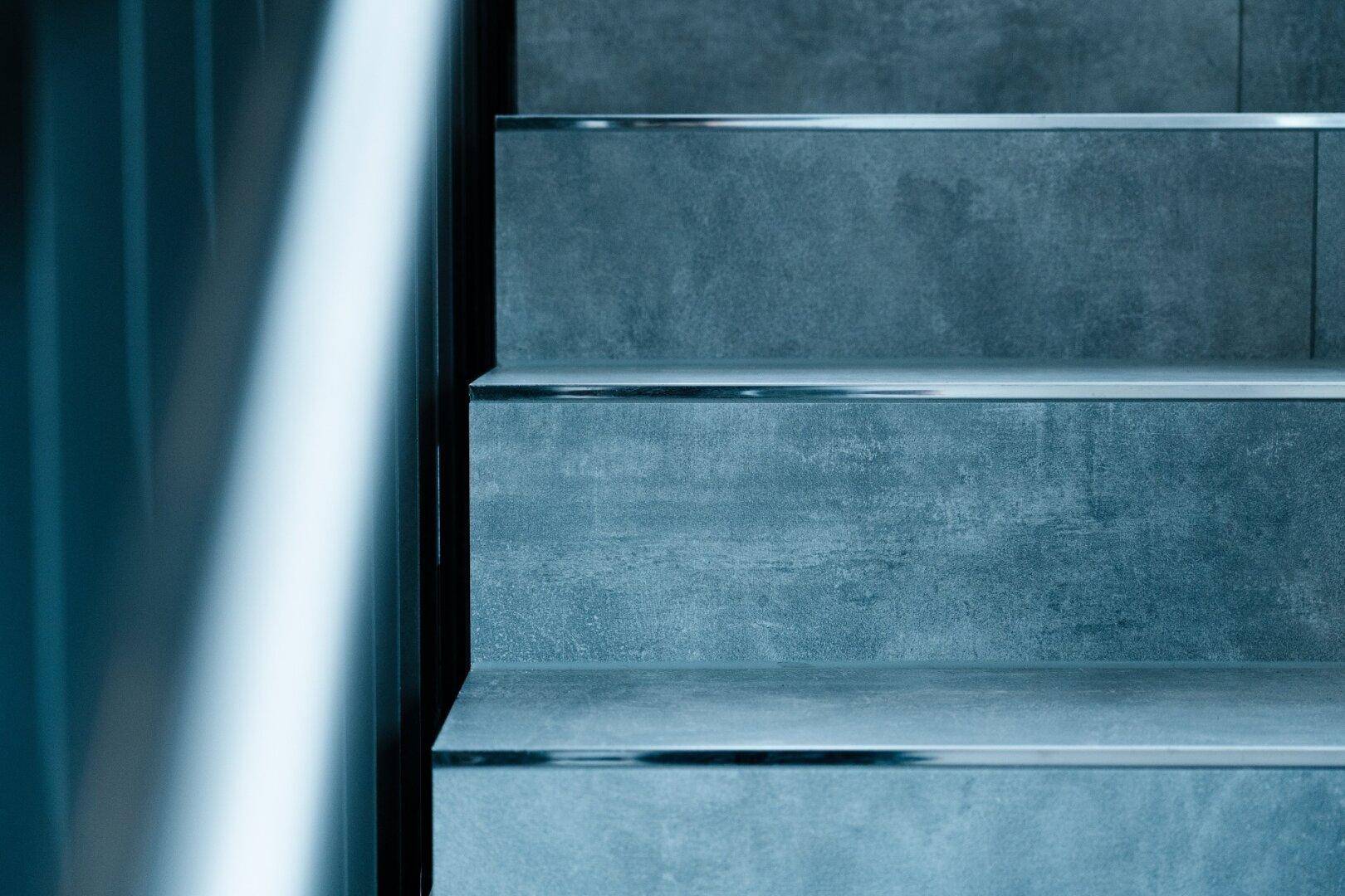 Detailansicht von Treppenstufen mit grauen Fliesen und eleganten Metallkanten.