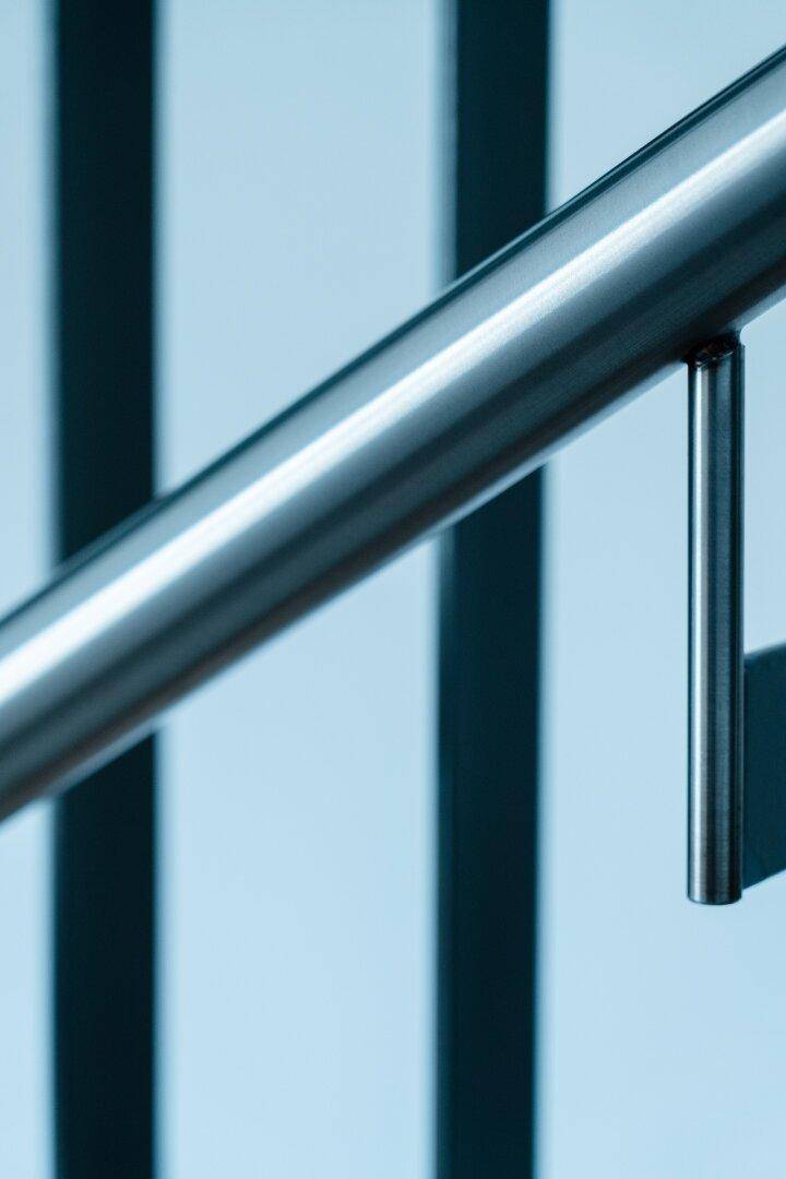 Nahaufnahme eines modernen, glänzenden Metallhandlaufs, der eine Treppe begleitet.