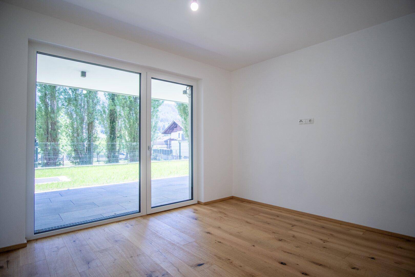 Heller Raum mit Holzboden und großem Terrassenzugang, bereit zur Einrichtung.